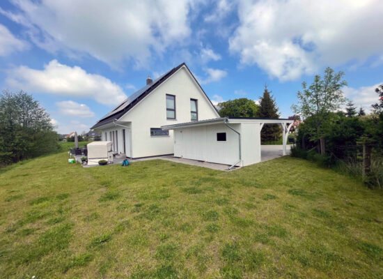 Freistehender Carport mit zwei Bögen, weiß deckend gestrichen und anthrazitfarbenem Flachdach. Die harmonische Farbgebung fügt sich perfekt in moderne Umgebungen ein.