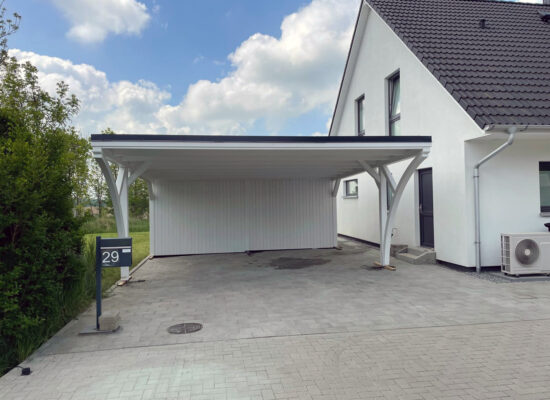 Rückseite des Carports mit geräumigem Schuppen und praktischem Dachüberstand. Solide Konstruktion, deckend weiß gestrichen und wetterbeständig verarbeitet.