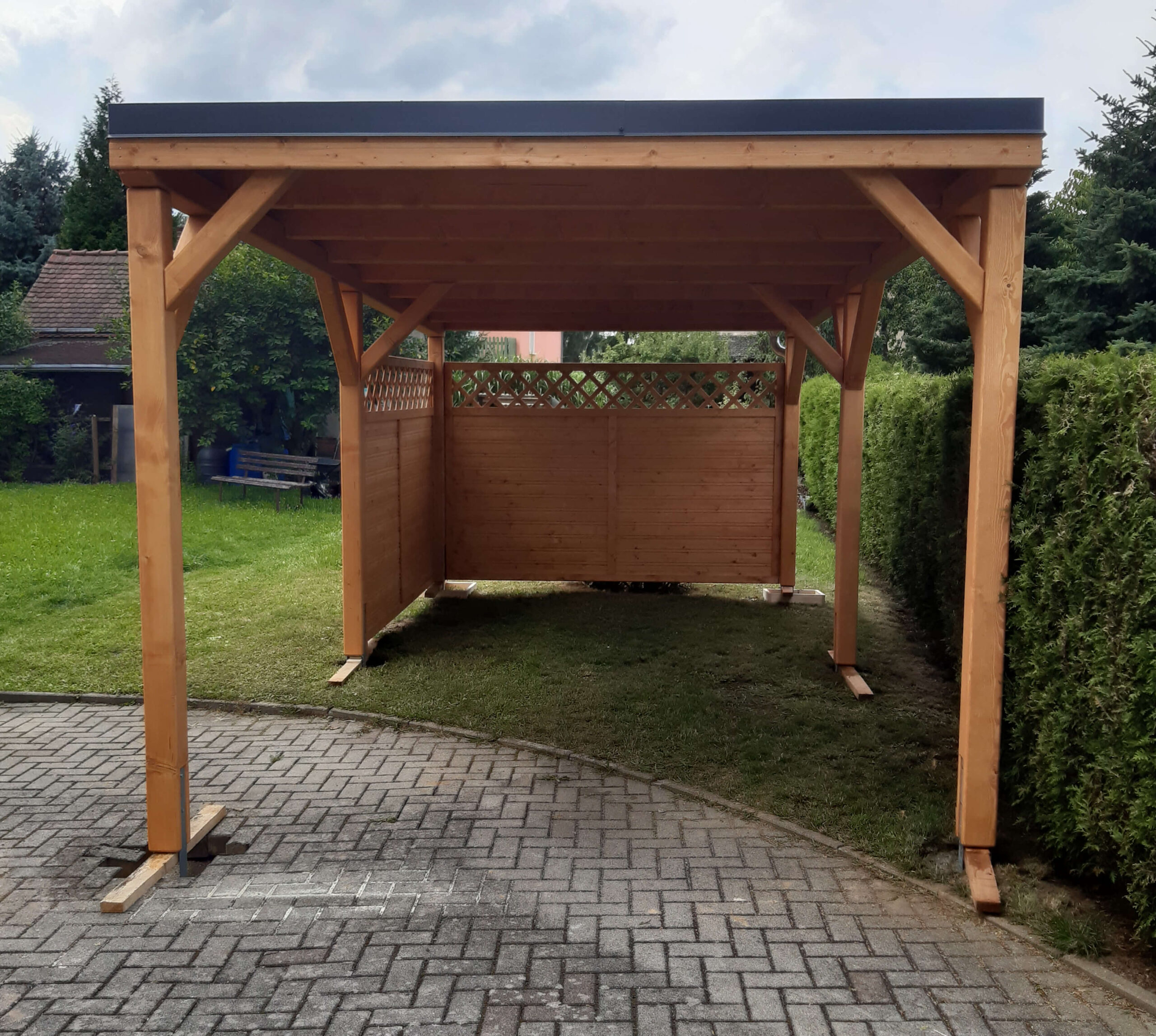 Einzelcarport mit Lamellenwand und Gitter, imprägniertes Holz, klassisches Design.