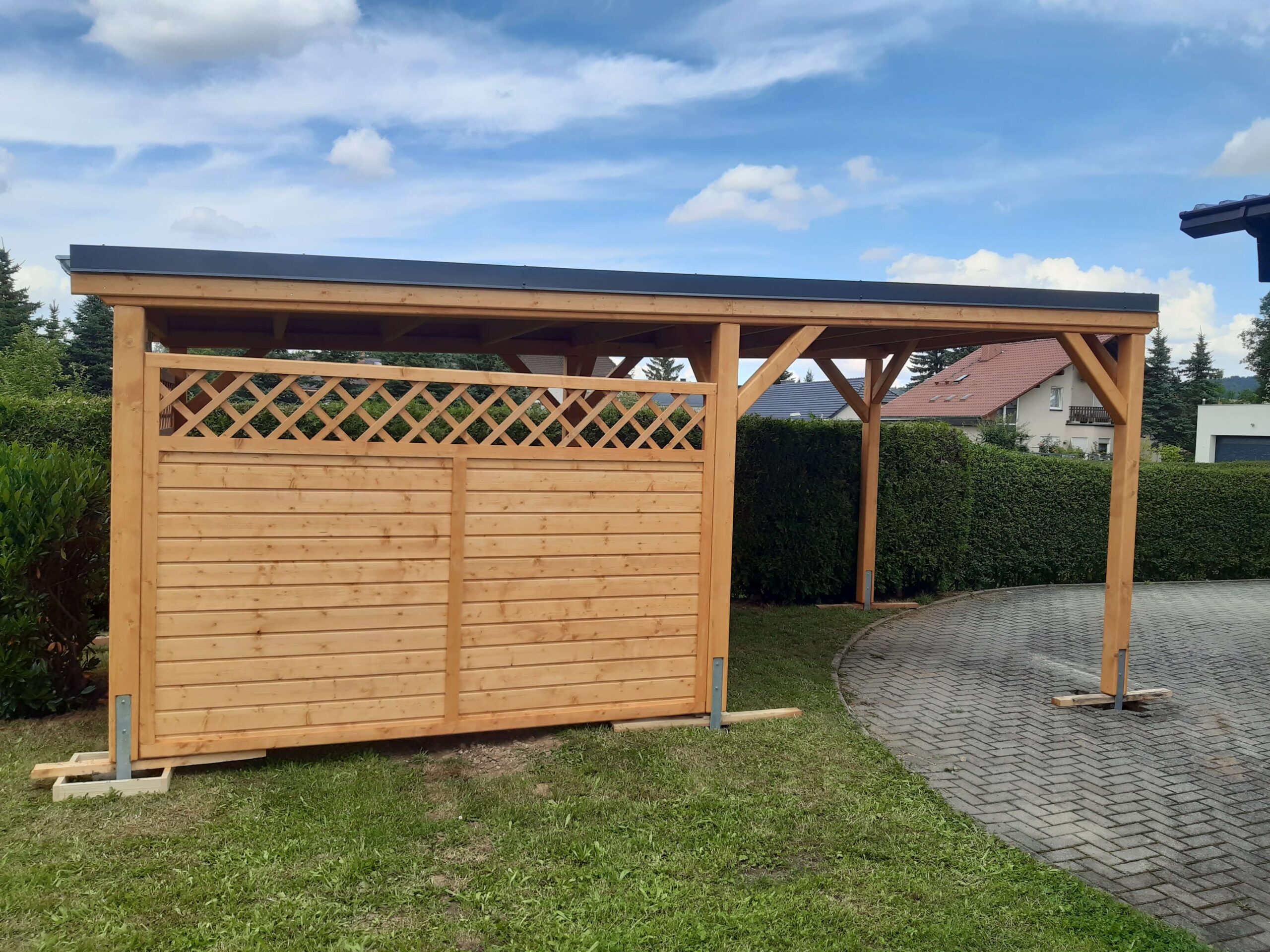 Einzelcarport mit Lamellenwand und Gitter, imprägniertes Holz, klassisches Design.