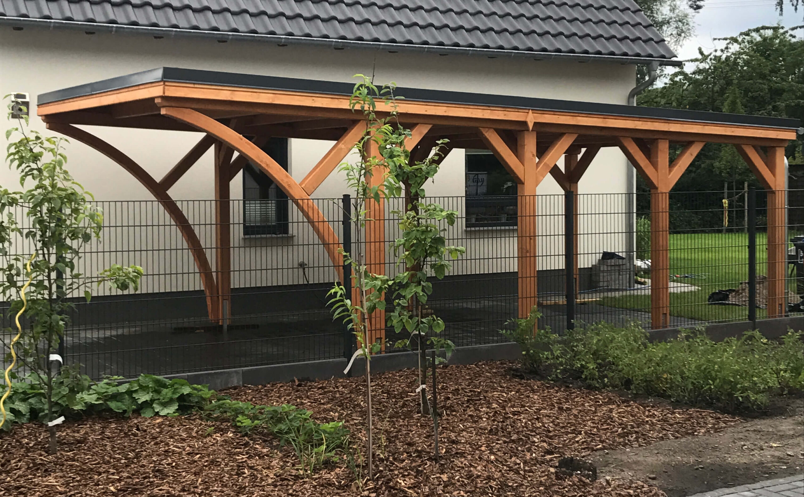 Carport mit Flachdach und stabiler Holzstruktur, gefertigt aus imprägniertem Holz. Die Konstruktion zeigt präzise Verarbeitung und solide Handwerksausführung.