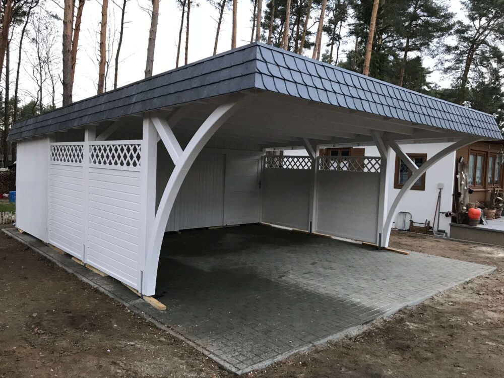 Seitliche Ansicht des Elegance Duo Carports mit Bögen und Holzpaneelzaun. Die Verbindung aus dekorativen Elementen und klarer Struktur wirkt elegant und ausgewogen.