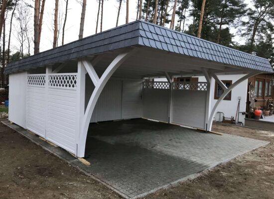 Seitliche Ansicht des Elegance Duo Carports mit Bögen und Holzpaneelzaun. Die Verbindung aus dekorativen Elementen und klarer Struktur wirkt elegant und ausgewogen.