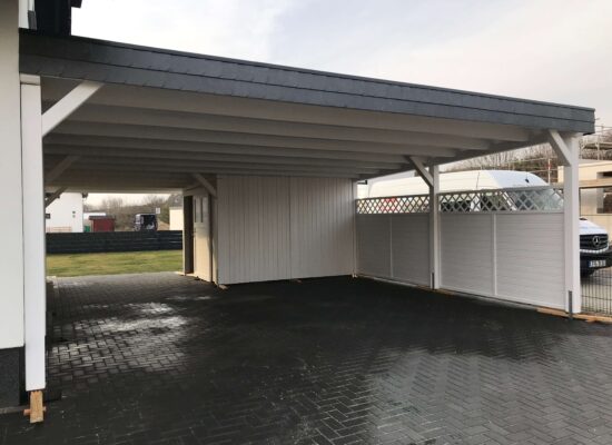 Frontansicht des FamilyLine Carports mit großem Schuppen und Walmdachblende. Weiß-Anthrazit-Oberfläche, klar strukturiert und ästhetisch ausgeführt.