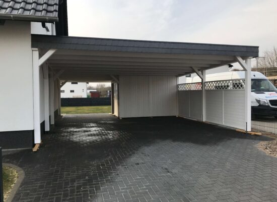 Doppelcarport mit Flachdach, weißer Struktur und anthrazitfarbenem Dachrand. Klare Proportionen und feine Holzverarbeitung prägen das Erscheinungsbild.