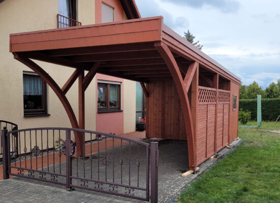 Einzelcarport mit Flachdach und zwei großen Bögen, gefertigt aus imprägniertem Mahagoniholz. Die Walmdachblende in Ziegelton unterstreicht den individuellen Charakter der Anlage.