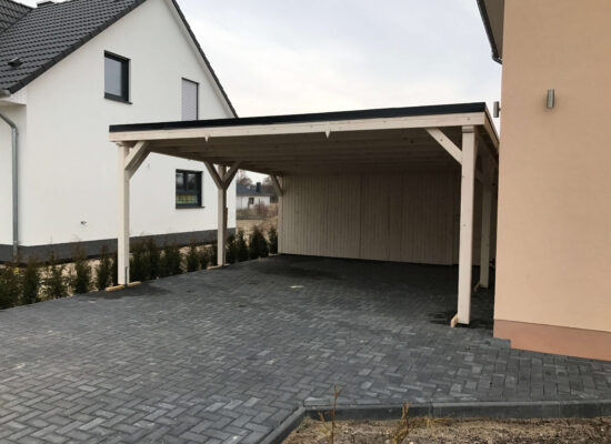 Carport aus hell imprägniertem Holz, präzise gefräste Konstruktionselemente, harmonisch verbaut. Jedes Detail zeigt sorgfältige Handwerksarbeit und Liebe zum Material.