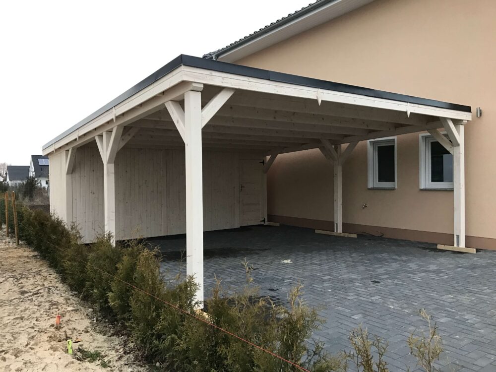 NaturCarport Classic aus hell imprägniertem Holz mit großem Geräteraum. Die klassische Form und die harmonische Front betonen handwerkliche Qualität und Langlebigkeit.