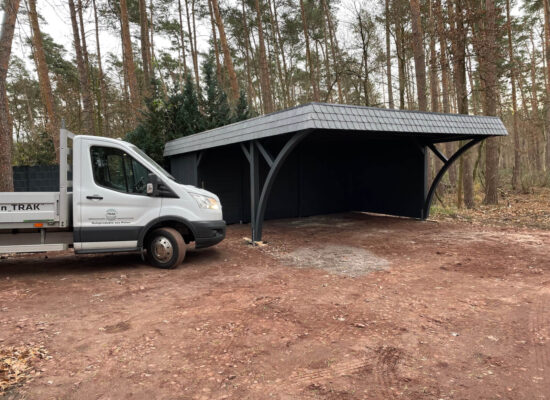 Premium-Carport DarkElegance mit Walmdachblende, in dunklem Waldgrün gestrichen. Die massiven Bögen und Pfosten vermitteln Stabilität und natürliche Eleganz.