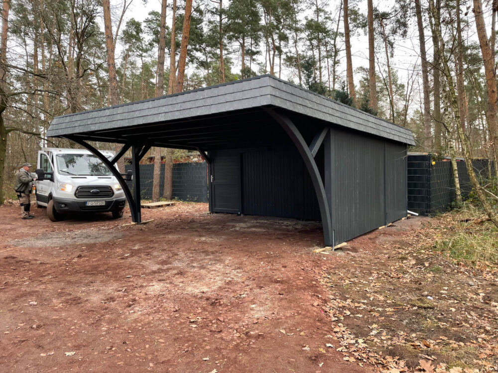 Carport DarkElegance mit geschlossener Seitenwand bis unter das Dach, dunkelgrün imprägniert. Solide Holzverarbeitung und klare Linien in perfekter Balance.