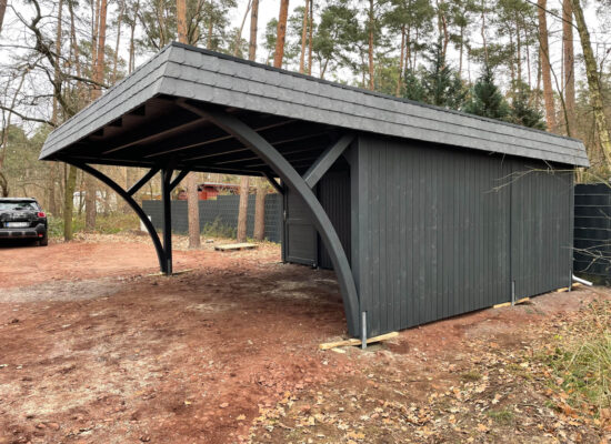 Seitenansicht des DarkElegance Carports mit massiver Wand und elegantem Bogen. Dunkle Farbgebung, kraftvolle Struktur und feine handwerkliche Details.
