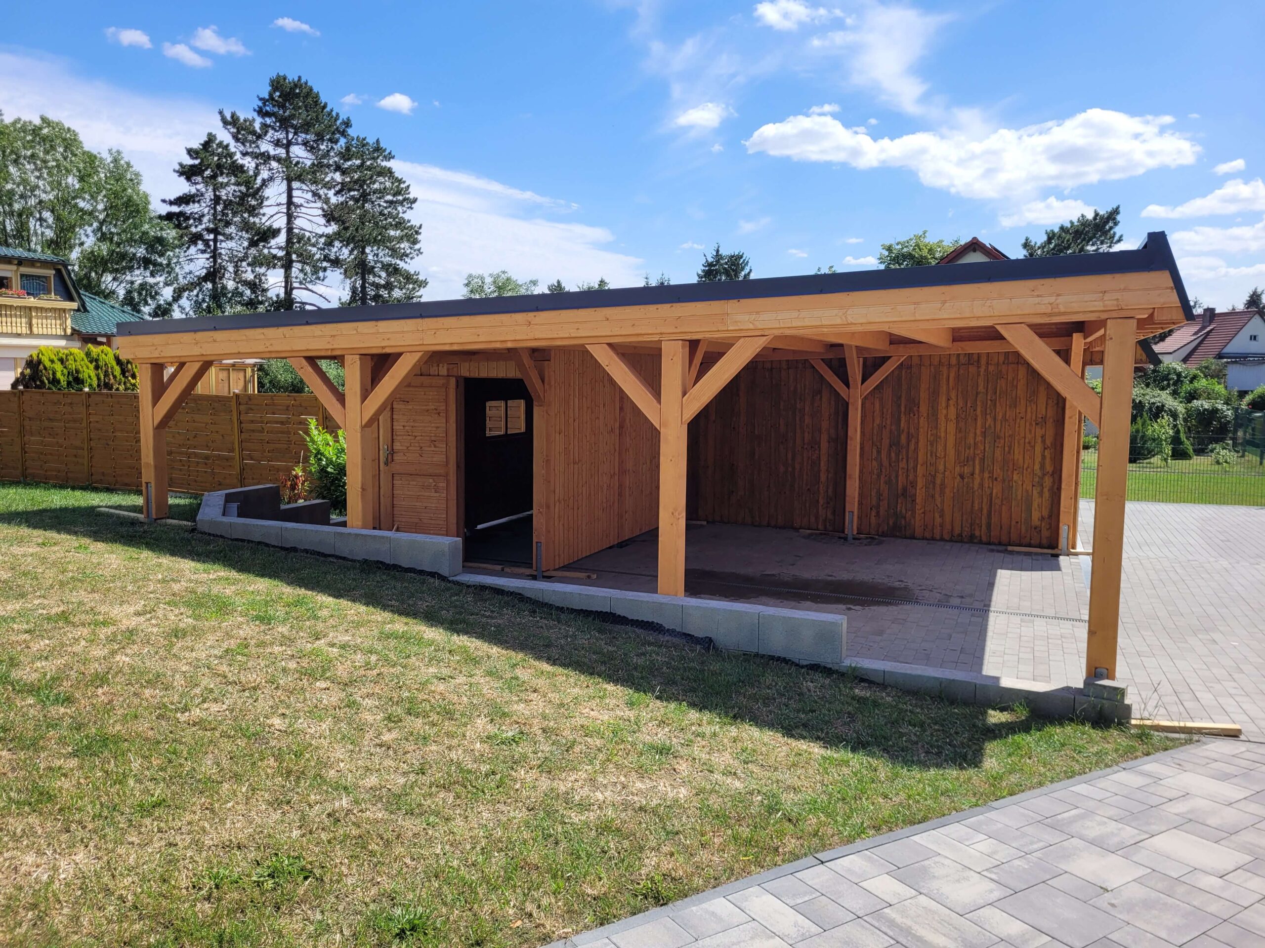 Doppelcarport mit Geräteraum, errichtet auf Gefälle und individuell an unebenen Boden angepasst. Die imprägnierte Holzkonstruktion bleibt stabil, dauerhaft und optisch harmonisch.