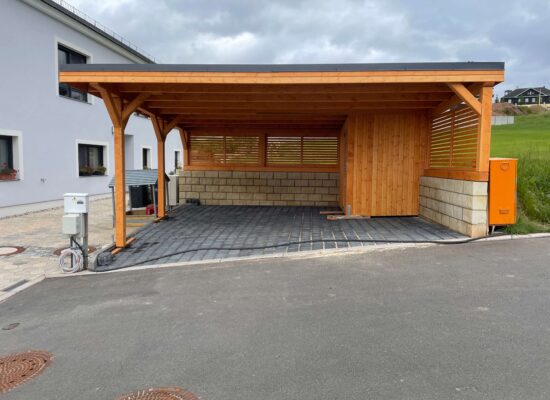 Carport mit Geräteraum und Lamellenwände, teils auf Holzunterbau errichtet. Das Projekt zeigt eine kreative Anpassung an anspruchsvolles Gelände.