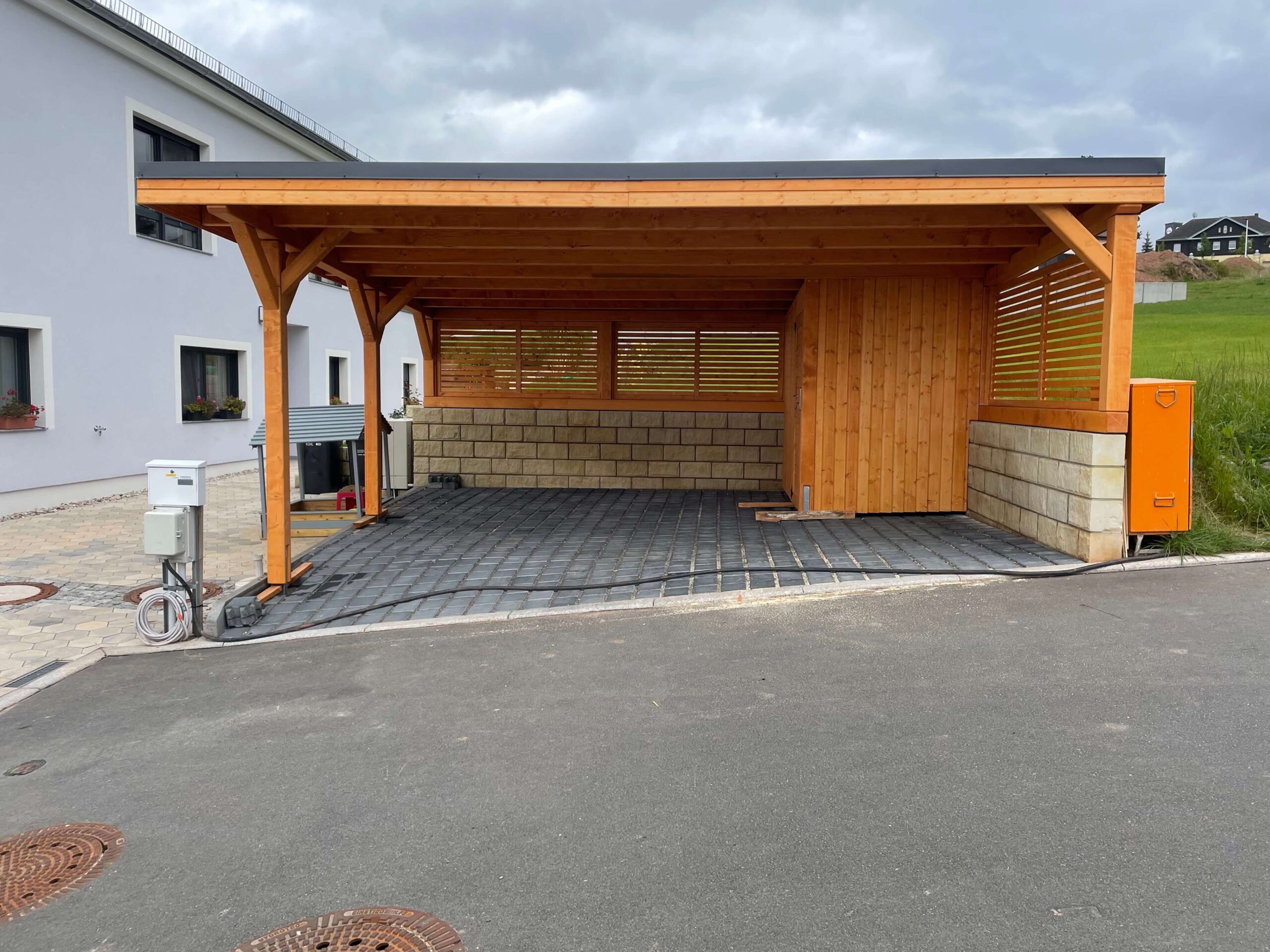 Moderner Carport mit Flachdach, Holz imprägniert, solide Bauweise mit großen Pfosten. Die klare Frontgestaltung betont Stabilität und handwerkliche Präzision.