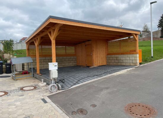 Flachdach-Carport mit Metallblende und integrierter Schuppenfläche. Durch die massive Konstruktion entsteht ein ausgewogenes Verhältnis von Funktion und Design.
