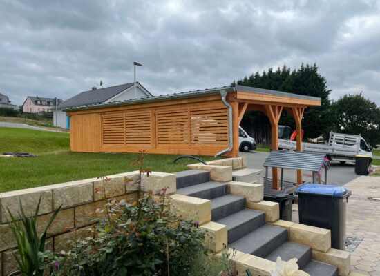 Rückseite des Carports mit Lamellenwand aus imprägniertem Holz, handgefertigt. Die vertikale Struktur verleiht Tiefe und moderne Leichtigkeit.