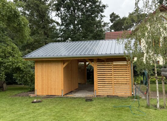 Seitenansicht des Carports mit Lamellenwand, Schuppen und verstärktem Trapezblechdach. Holz in Naturholzmaserung, robust und ästhetisch zugleich.