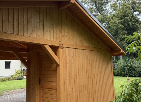 Rückansicht des Carports mit integrierter Schuppenfläche, sauber verarbeitet in Naturholzoptik. Massive Struktur, zeitloses Design.