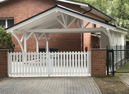 AlpineXL Carport mit klassischem Landhauszaun, harmonisch abgestimmt in Farbe und Form. Weißer Holzbau, der sich perfekt in das Grundstück einfügt.