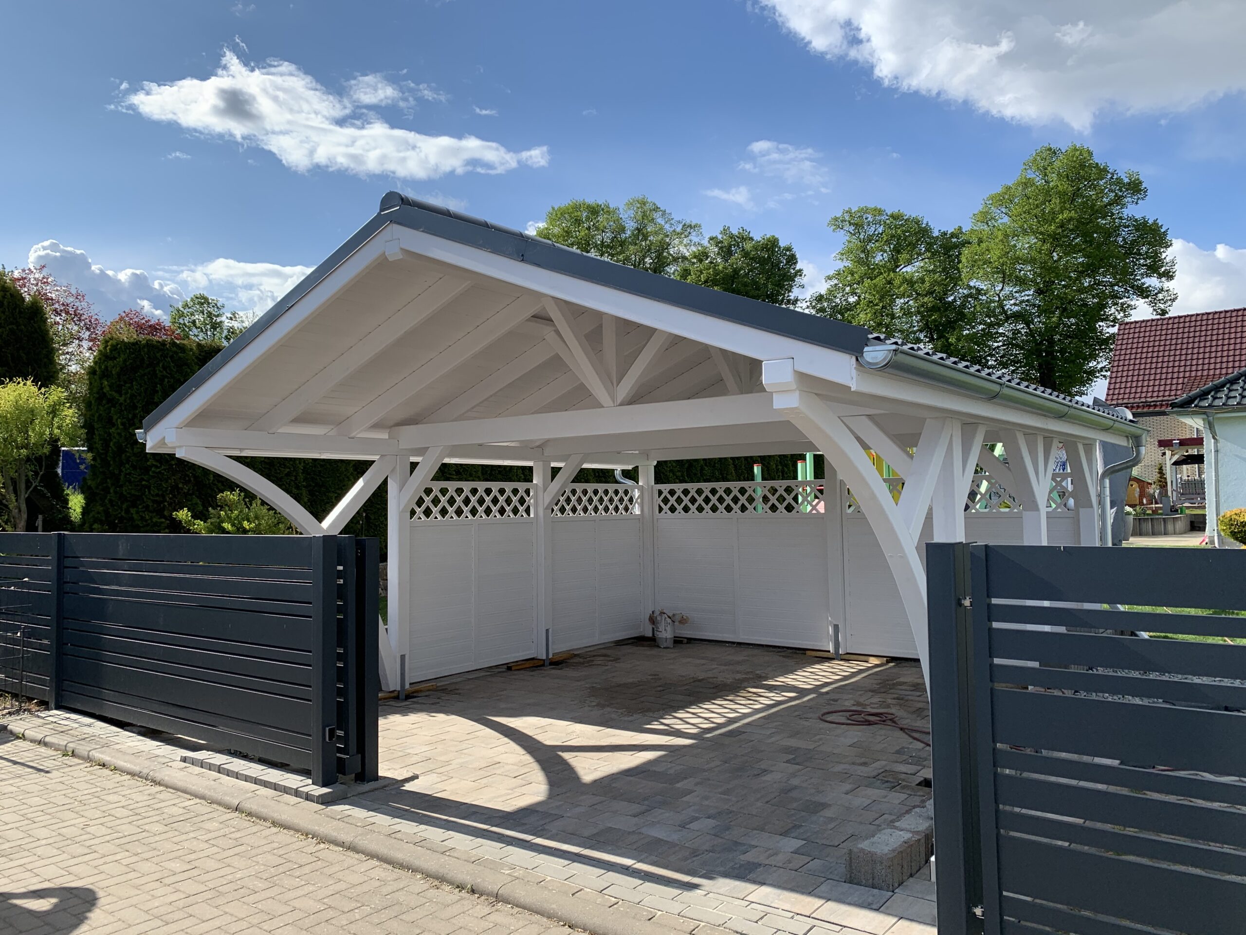 Premium Doppelcarport Weiß mit anthrazitfarbenem Vivaldi-Dach und weißen Rundbögen. Die massive Holzstruktur und harmonische Farbgestaltung fügen sich perfekt ins Grundstück ein.