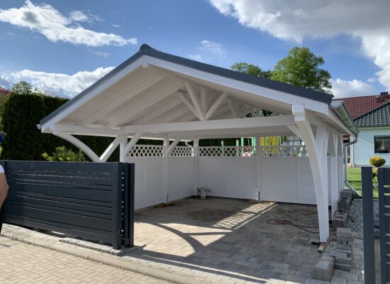 Satteldach Doppelcarport mit weißer Bretterschalung und klassischem Rundbogen-Design. Die feinen Linien und solide Ausführung zeigen echte Handwerkskunst.