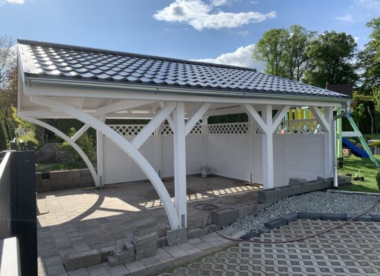 Seitenansicht des Premium Doppelcarports Weiß mit integrierter Zaunverkleidung. Die weißen Paneele und das anthrazitfarbene Dach schaffen ein elegantes, harmonisches Gesamtbild.