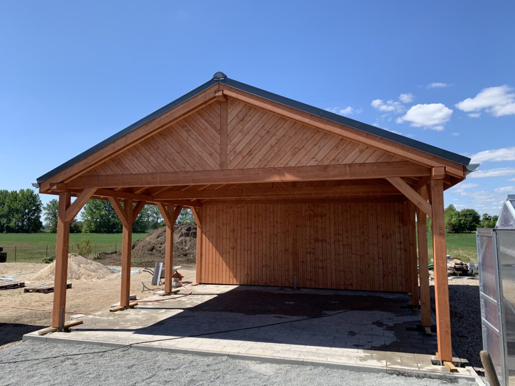 Hochwertiger Country Carport mit schräger Giebelverkleidung und Naturholzstruktur. Die warme Holzfarbe und sichtbare Maserung unterstreichen den rustikalen Charakter.