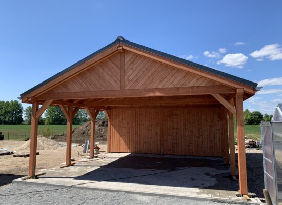 Hochwertiger Country Carport mit schräger Giebelverkleidung und Naturholzstruktur. Die warme Holzfarbe und sichtbare Maserung unterstreichen den rustikalen Charakter.