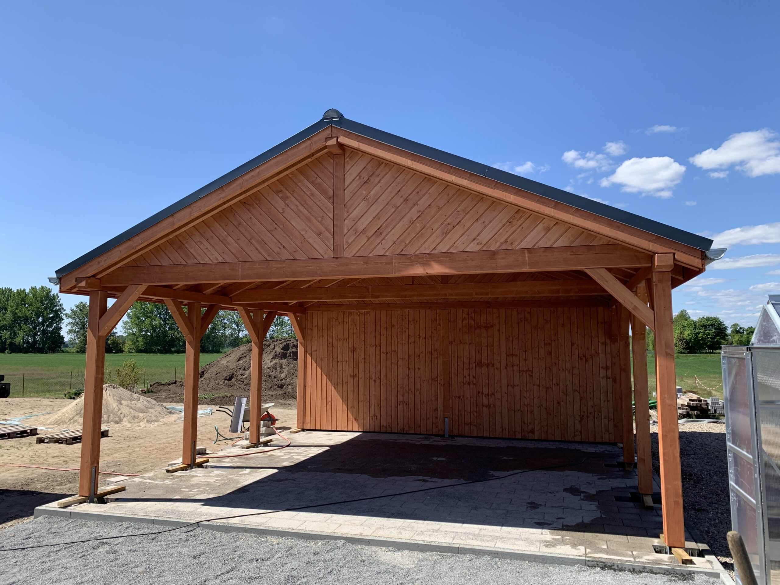 Hochwertiger Country Carport mit schräger Giebelverkleidung und Naturholzstruktur. Die warme Holzfarbe und sichtbare Maserung unterstreichen den rustikalen Charakter.