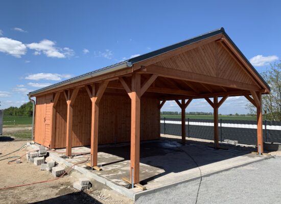 Country Carport mit Satteldach und großzügigem Schuppenbereich, aus naturbelassenem Holz gefertigt. Die klare Linienführung wirkt ruhig und harmonisch.