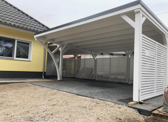Carport Plus mit Bretterschalung und integriertem Geräteraum, weiß gestrichen. Die saubere Dachunterseite und passgenauen Türen zeugen von hochwertiger Verarbeitung.