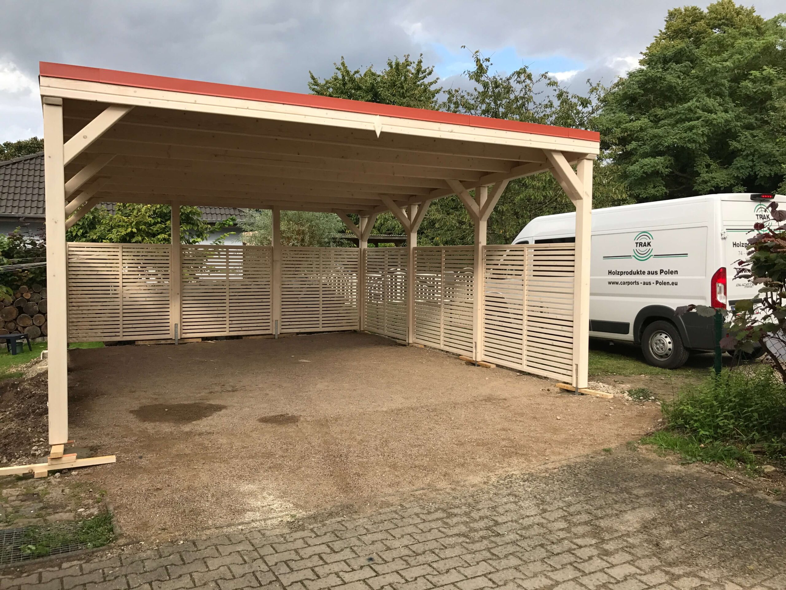 Flachdach-Carport CamperLine, extra hoch und massiv gebaut, hell imprägniertes Holz. Drei Seiten mit Lamellen als Windschutz – funktional und modern zugleich