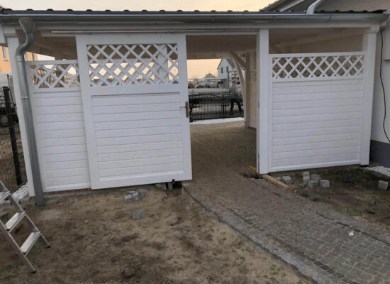 Schiebetür zum Garten im Stil der Zaunanlage – vertikale Holzleisten mit dekorativem Gittereinsatz. Weiß gestrichene Oberfläche und handgefertigte Details.