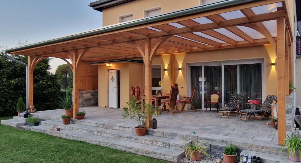 Terrassenüberdachung mit eleganten Bögen und klarer Linienführung. Massive Holzpfosten und Naturholzstruktur in perfekter Balance.