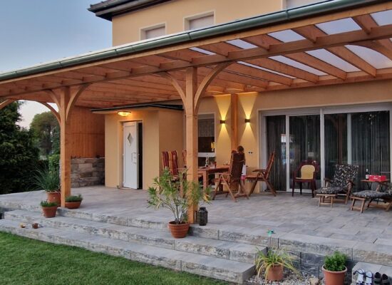 Terrassenüberdachung mit eleganten Bögen und klarer Linienführung. Massive Holzpfosten und Naturholzstruktur in perfekter Balance.