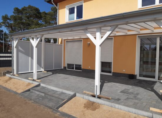 Seitenansicht der weißen Terrassenüberdachung mit milchigem Windschutz. Klare Linien, hochwertiges Handwerk und dezente Lichtwirkung.