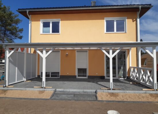 Frontansicht der Terrassenüberdachung mit transparentem Dach, Windschutz und Kreuzgeländer. Symmetrisch, harmonisch und handwerklich präzise gefertigt.