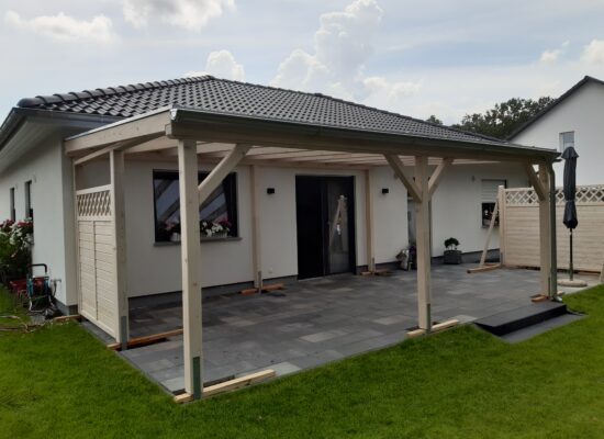 Klassische Terrassenüberdachung aus hell imprägniertem Holz mit seitlichem Windschutz. Milchige Doppelstegplatte für angenehmes Licht und Schutz bei Wind und Wetter.