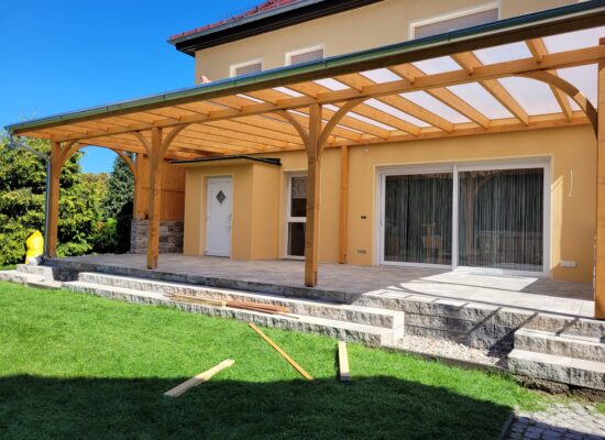 Terrassenüberdachung in Abendstimmung mit Gartenmöbeln und Beleuchtung. Die milchige Platte erzeugt sanftes, atmosphärisches Licht.