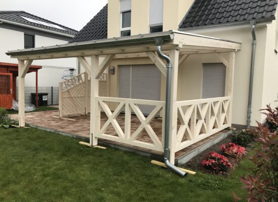 Seitenansicht der Terrassenüberdachung mit klassischem Kreuzgeländer aus hellem Holz. Stabil, handwerklich präzise und ästhetisch ausgeführt.