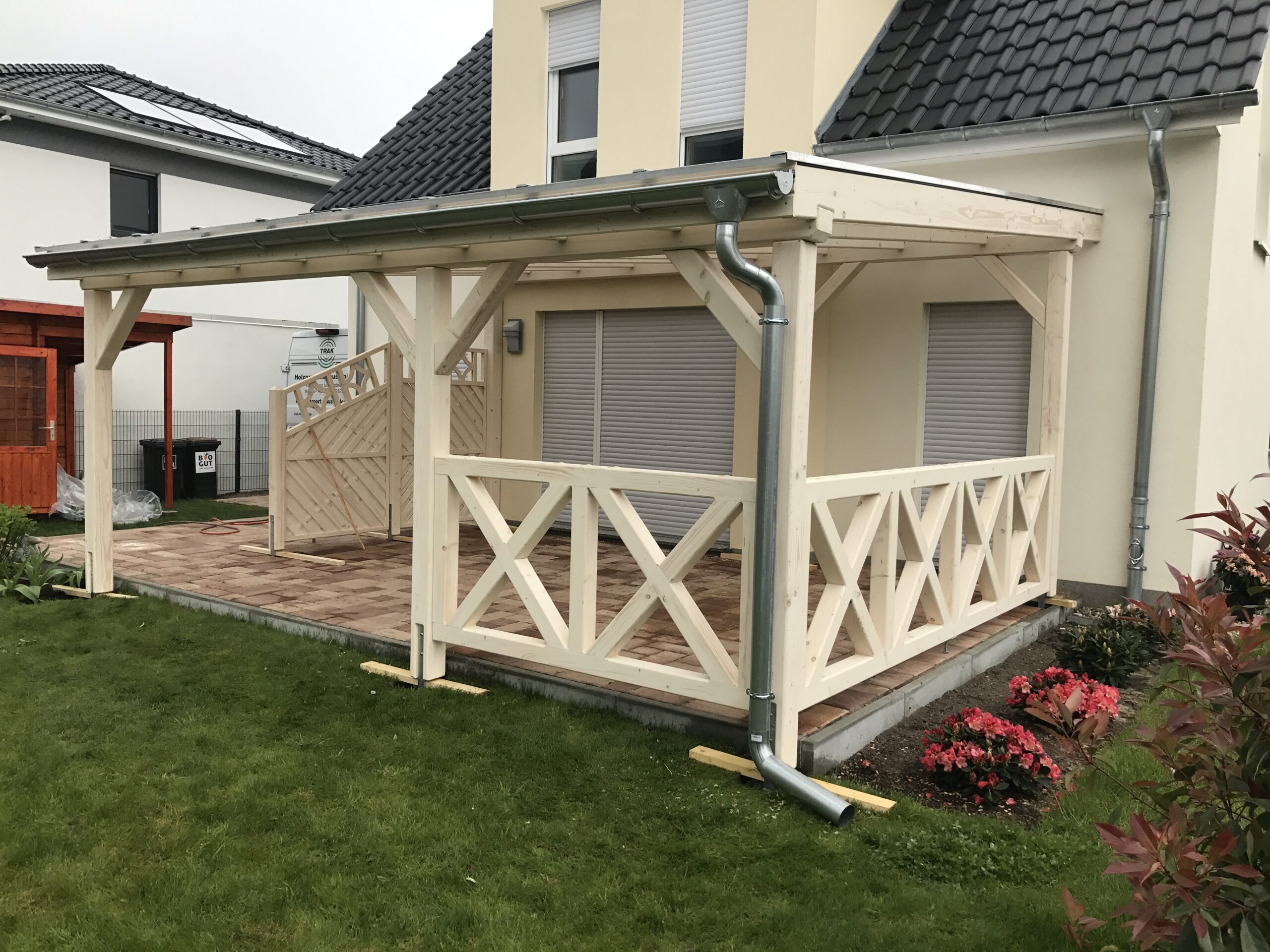 Seitenansicht der Terrassenüberdachung mit klassischem Kreuzgeländer aus hellem Holz. Stabil, handwerklich präzise und ästhetisch ausgeführt.