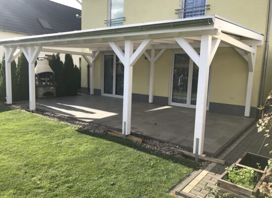 Seitenansicht der weißen Holz-Terrassenüberdachung mit brauner Doppelstegplatte. Perfekte Proportionen und sanfte Linienführung.