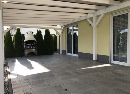 Innenansicht der Terrassenüberdachung mit abgerundeten Kanten und sichtbarer Holzstruktur. Das warme Licht der braunen Doppelstegplatte schafft eine gemütliche Atmosphäre.