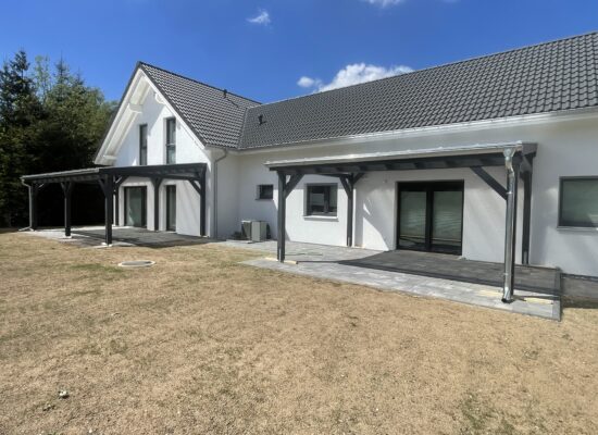 Zwillings-Überdachungen aus Holz mit klarer Struktur und transparenter Dachfläche. Funktionalität trifft auf dezente Eleganz.