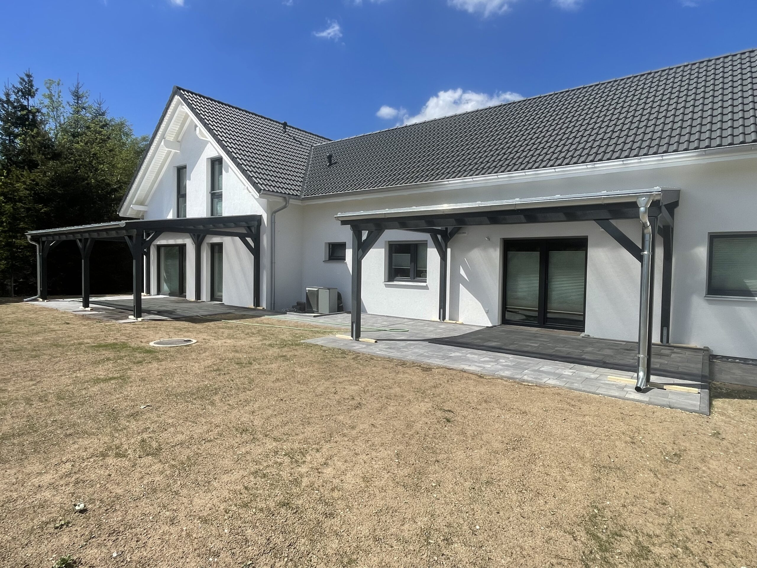 Zwillings-Überdachungen aus Holz mit klarer Struktur und transparenter Dachfläche. Funktionalität trifft auf dezente Eleganz.