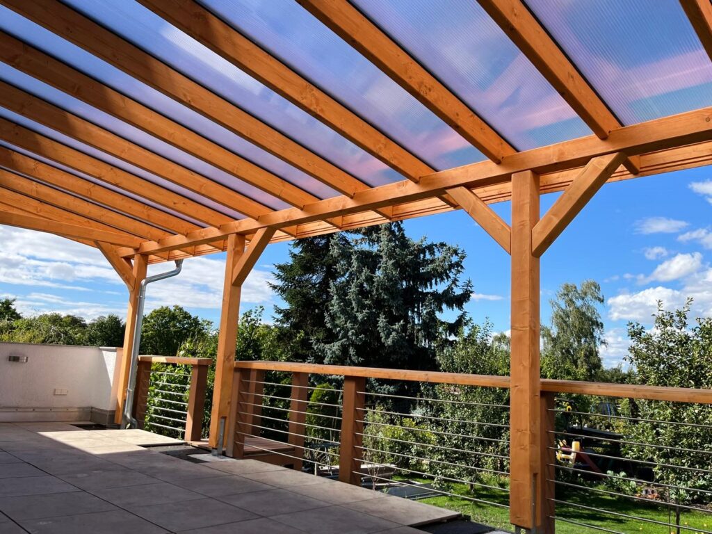 Innenansicht mit massiven Holzstützen und Dachüberstand. Großzügige Fläche, perfekt für gemütliche Abende im Freien.