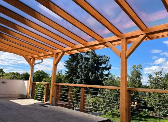 Innenansicht mit massiven Holzstützen und Dachüberstand. Großzügige Fläche, perfekt für gemütliche Abende im Freien.