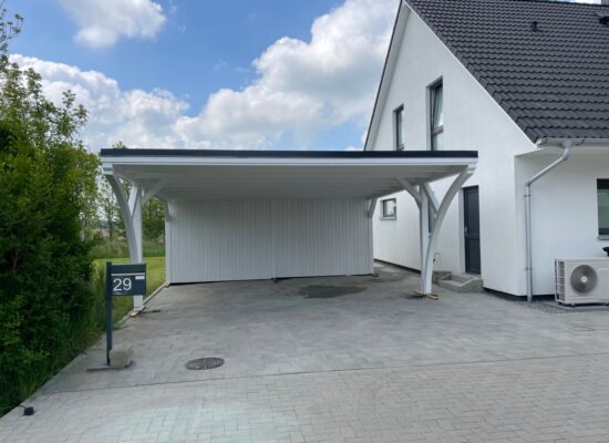 Freistehender Carport mit zwei Bögen, weiß deckend gestrichen und anthrazitfarbenem Flachdach. Die harmonische Farbgebung fügt sich perfekt in moderne Umgebungen ein.