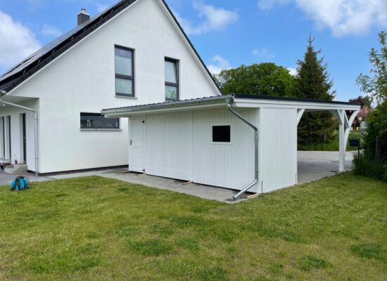 Rückseite des Carports mit geräumigem Schuppen und praktischem Dachüberstand. Solide Konstruktion, deckend weiß gestrichen und wetterbeständig verarbeitet.